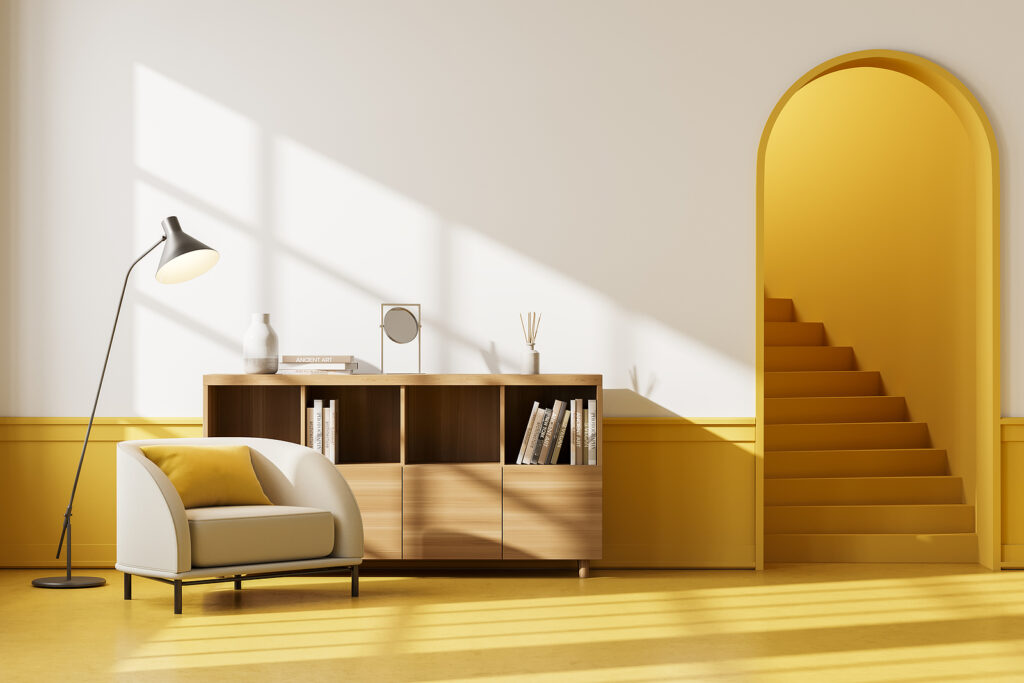 Apartment interior with beige seat and drawer with books and decoration, yellow floor.