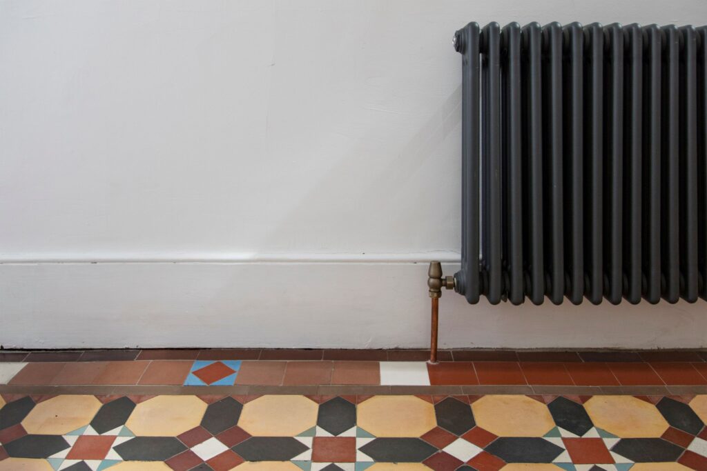 Victorian hallway with charcoal column radiator and mosaic tiliing