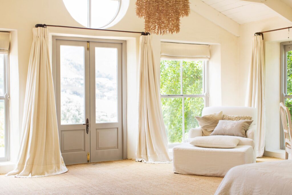 Beige and cream living room with big windows and curtains. 