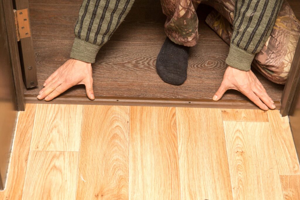 person fitting internal door threshold strip 