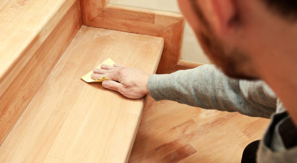 Man sanding wooden staircase 